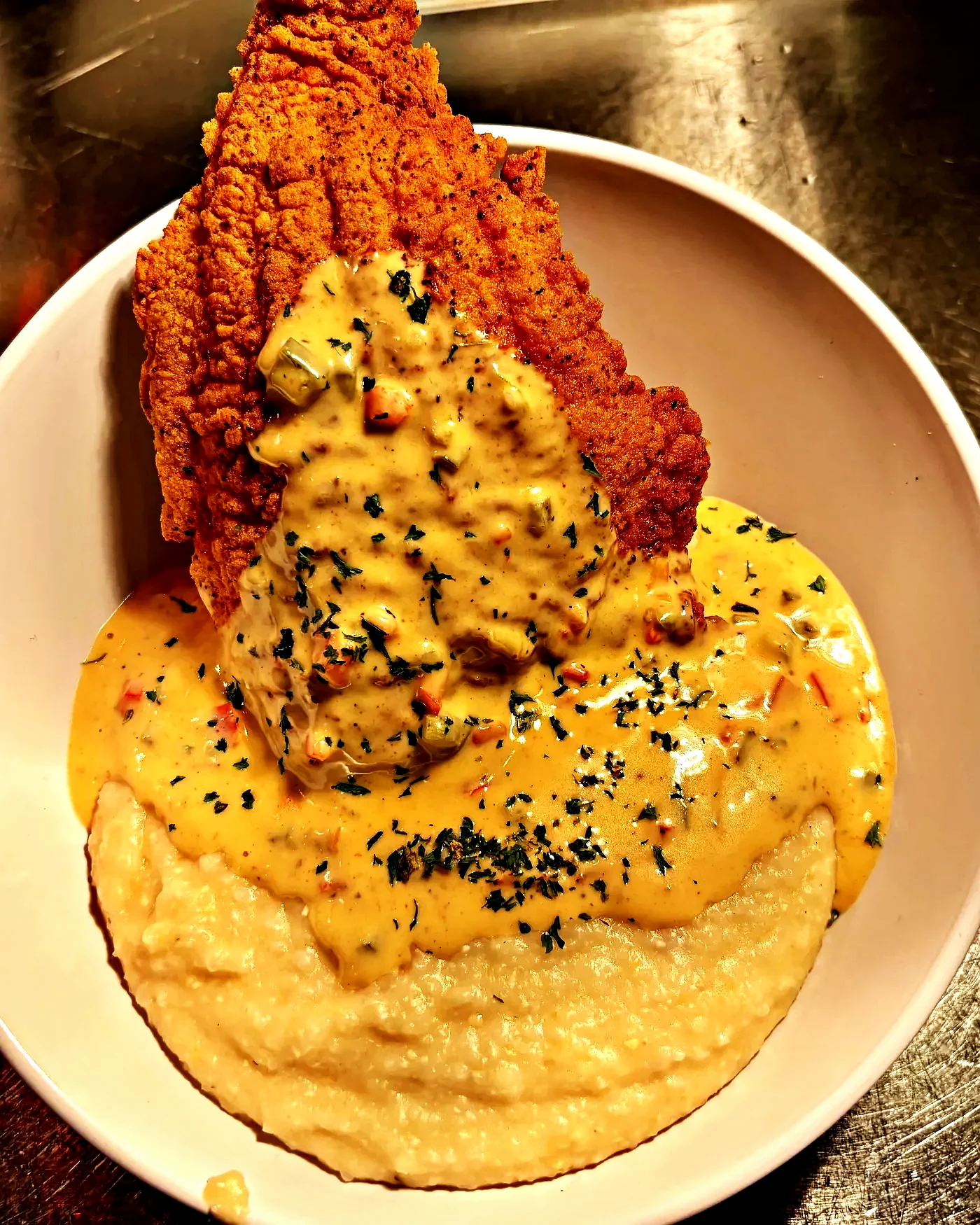 Fried catfish over stone-ground grits with creole cream sauce