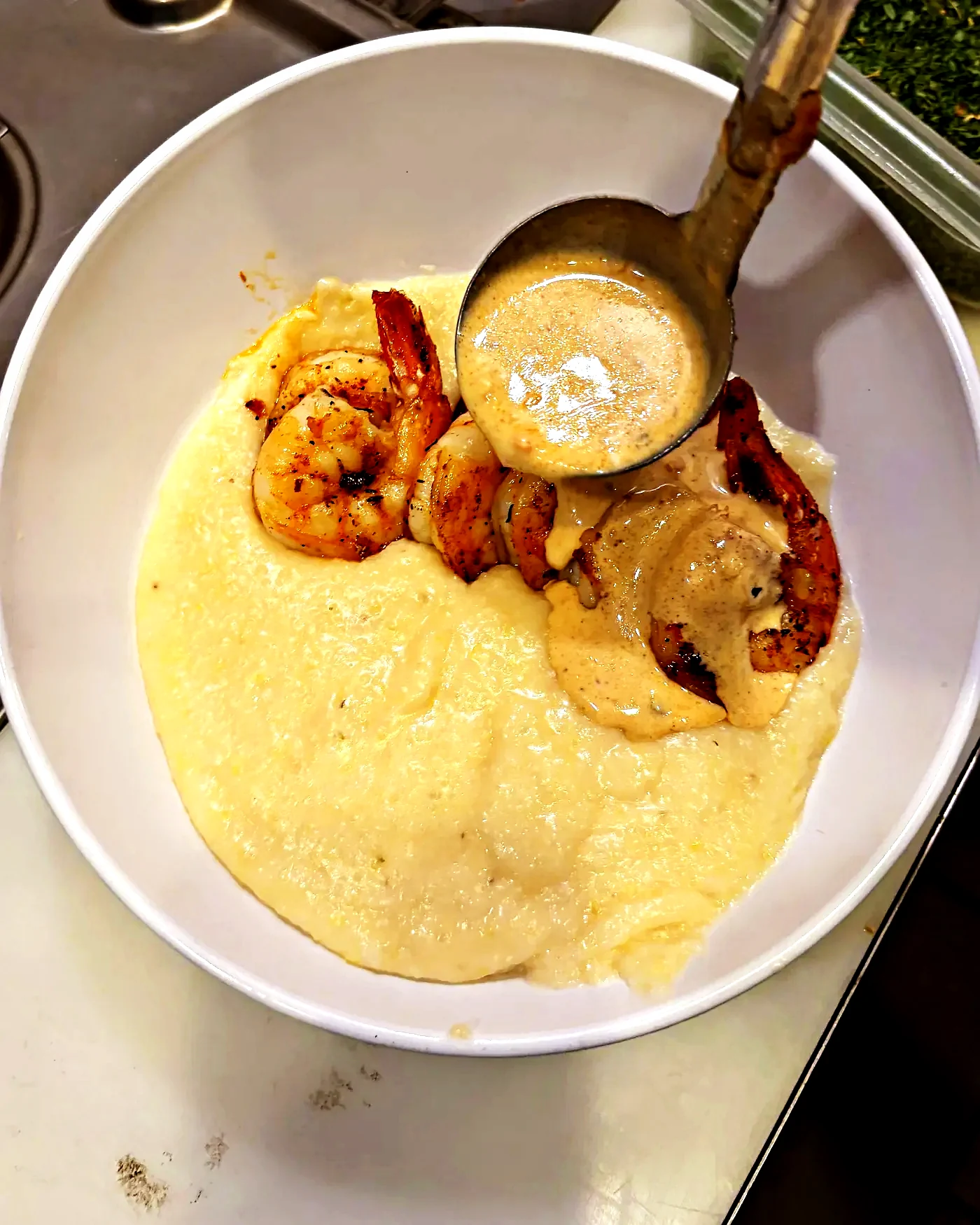 Shrimp and grits being finished with cream sauce